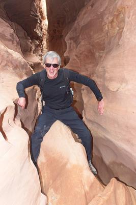 Father climbing over a chockstone in Little Wild Horse Canyon